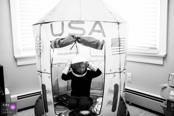 Photo by: <a href="https://www.fpja.com/documentary-family-photography-contests/korri-crowley/boston/2069136">Korri Crowley - United States</a> A little boy plays inside a large, play rocket ship in this photograph created by a Boston, MA family photojournalist.