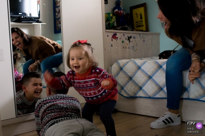 Photo by: <a href="https://www.fpja.com/documentary-family-photography-contests/morgana-secco/london/2069436">Morgana Secco - United Kingdom</a> A mother and her son and daughter laugh as they play around in this FPJA award-winning image captured by a London, England family photographer.