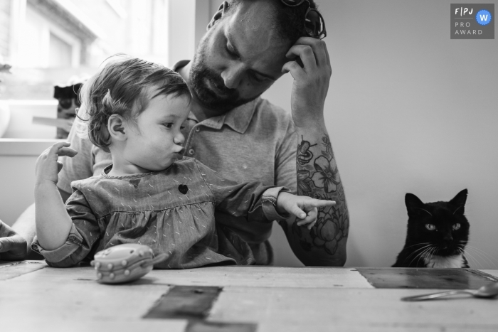 Un père regarde sa fille alors qu’elle pointe un chat sur cette photo enregistrée par un photographe de famille de style documentaire primé aux Pays-Bas.