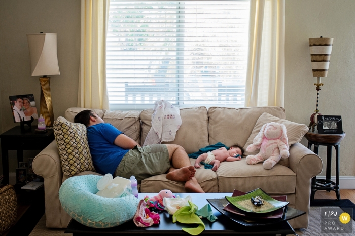 Un père dort sur un canapé à côté de son bébé sur cette photo réalisée par un photographe de famille documentaire de Key West, en Floride.