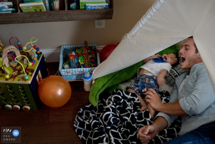 A father plays with his son on his bed as he laughs in this image created by a Key West, FL family photographer.