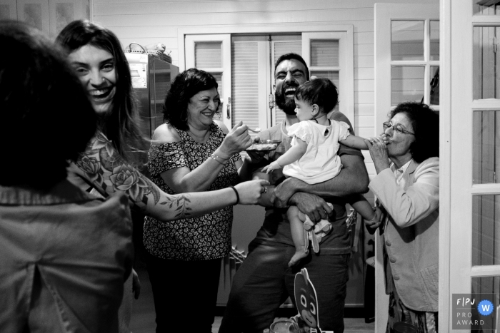 Une famille se rassemble autour d'une petite fille pendant que l'une d'entre elles la nourrit dans cette image capturée par un photojournaliste de la famille de Florianopolis.