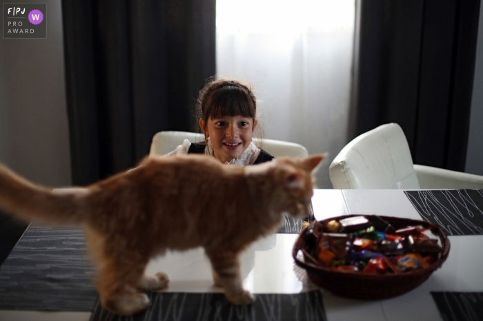 Une petite fille regarde un chaton renifler un bol de bonbons sur cette photo primée d'un photographe de famille de Saint-Pétersbourg, en Russie.