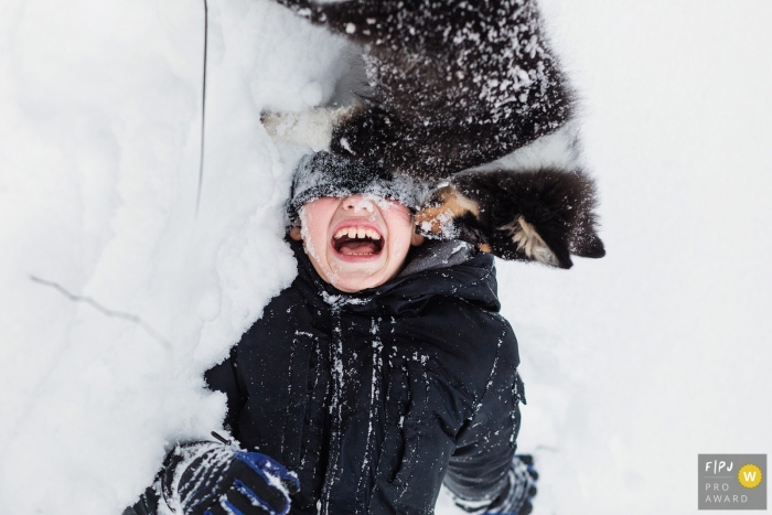 Un garçon joue dans la neige avec son chiot sur cette photo enregistrée par un photographe de famille de style documentaire primé à Saint-Pétersbourg, en Russie.