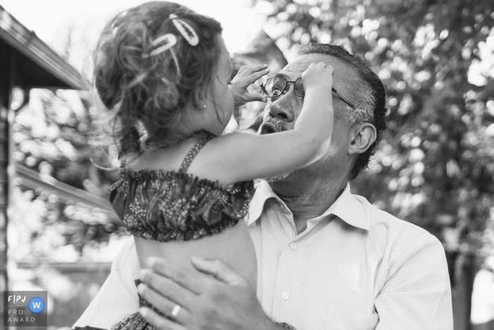 Une petite fille essaie d'enlever les lunettes de son grand-père sur cette photographie créée par un photojournaliste de la famille de Seattle, WA.