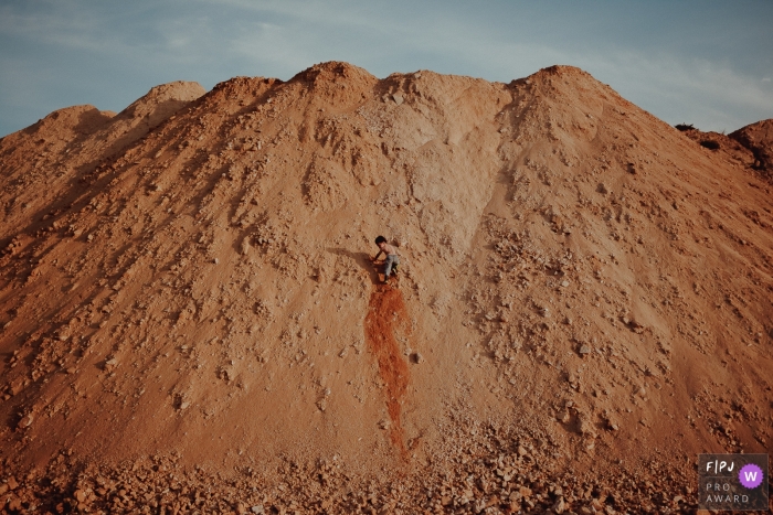 Photo by: <a href="https://www.fpja.com/documentary-family-photography-contests/adrieli-cancelier/curitiba/2072696">Adrieli Cancelier - Brazil</a> A young boy tries to climb up a large dune in this photo by a Curitiba, Parana family photojournalist.