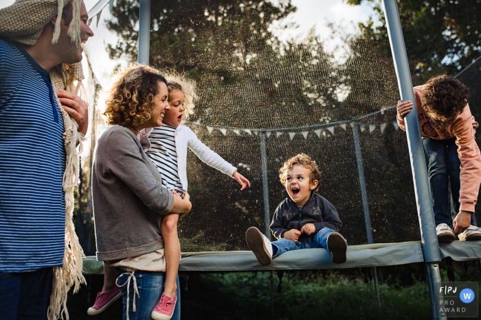 Photo by: <a href="https://www.fpja.com/documentary-family-photography-contests/emilie-marchandise/brabant-wallon/2072916">Emilie Marchandise - Belgium</a> A mother and father laugh as their son sits on a trampoline in this photo by a Wallonie family photojournalist.