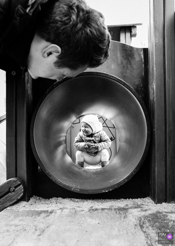 Un père regarde un enfant dans un tunnel de terrain de jeu sur cette photo en noir et blanc d'un photojournaliste de la famille de Basse-Silésie.