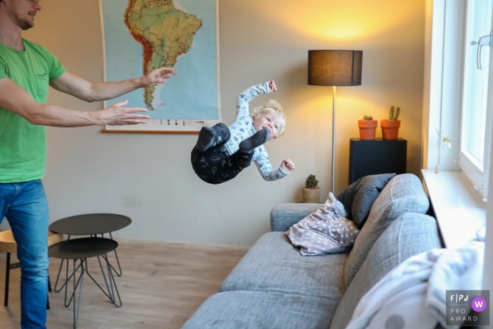 Photo by: <a href="https://www.fpja.com/documentary-family-photography-contests/sandra-van-der-meulen/noord-holland/2074081">Sandra van der Meulen - Netherlands</a> A boy is midair as his father tosses him onto a couch in this photo by a Netherlands family photojournalist.