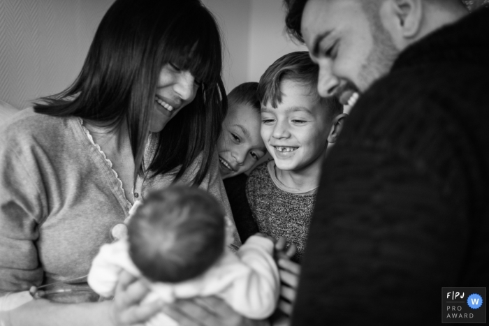 Les parents présentent leur nouveau frère à leurs deux jeunes garçons sur cette photo en noir et blanc réalisée par un photojournaliste de la famille romaine.