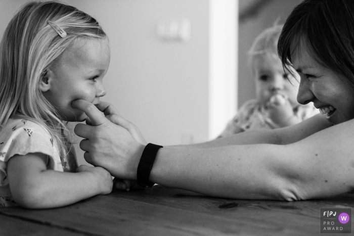 Photo by: <a href="https://www.fpja.com/documentary-family-photography-contests/liesbeth-parlevliet/zuid-holland/2074681">Liesbeth Parlevliet - Netherlands</a> A mother pinches her daughter's cheeks in this black and white photo by a Netherlands family photojournalist.