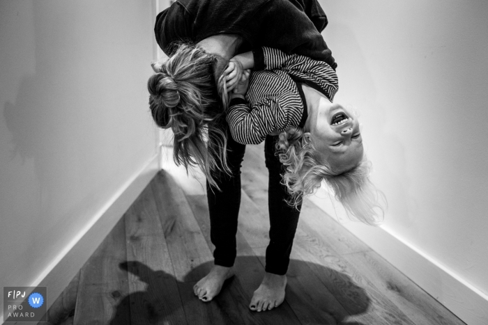 Photo by: <a href="https://www.fpja.com/documentary-family-photography-contests/liv-tomkins/amsterdam/2075036">Liv Tomkins - Netherlands</a> A mother blows raspberries on her daughter's stomach in this black and white photo by an Amsterdam family photojournalist.