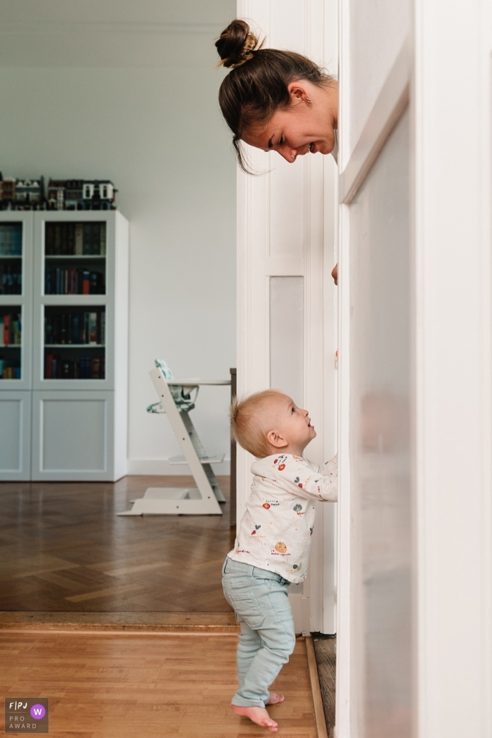 Une mère jette un coup d'œil par dessus une porte de son bébé dans cette image, réalisée par un photographe de famille de Gelderland, NL