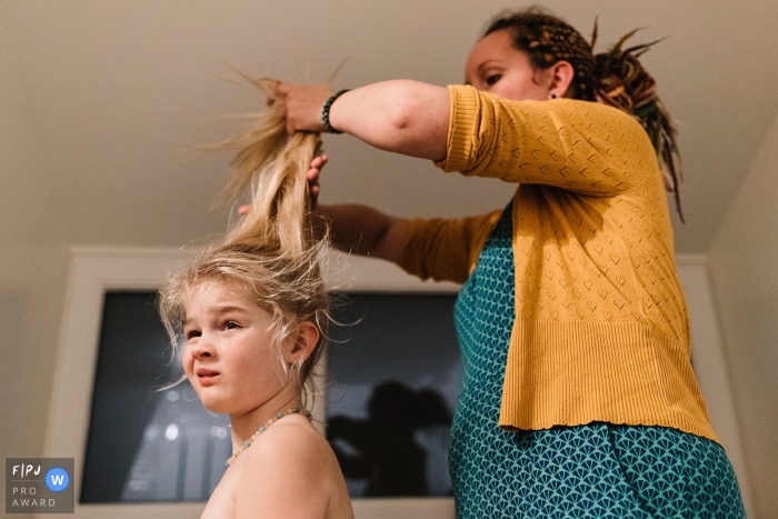 Une mère travaille à mettre les cheveux de sa fille en queue de cheval sur cette photo par un photojournaliste de la famille Gelderland, Pays-Bas.