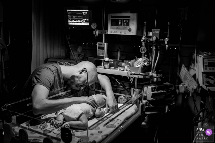 Photo by: <a href="https://www.fpja.com/documentary-family-photography-contests/marjolein-roossien/groningen/2077856">Marjolein Roossien - Netherlands</a> A father puts his hand on his baby's back in the hospital in this black and white photo by a Groningen, Netherlands birth photographer.