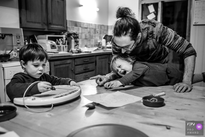 Photo by: <a href="https://www.fpja.com/documentary-family-photography-contests/nadine-court/savoie/2078086">Nadine Court - France</a> A father tries to calm down his daughter who wants her brother's toy in this black and white image by a Savoie family photographer.