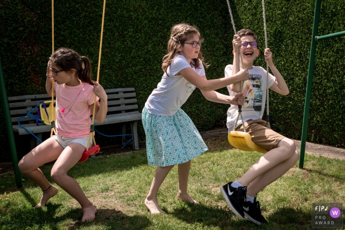 Trois enfants jouent sur une balançoire à l'extérieur sur cette photo d'un photographe de la famille nantaise.