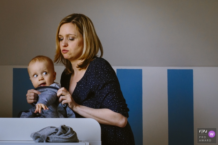 Photo by: <a href="https://www.fpja.com/documentary-family-photography-contests/rosa-engel/aachen/2079521">Rosa Engel - Germany</a> A baby boy makes a face as his mother tries to dress him in this image created by an Aachen family photographer.