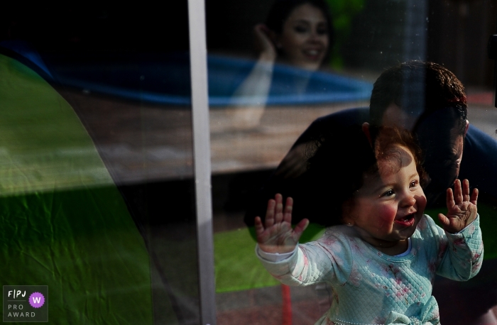 Une petite fille regarde son père dehors par la fenêtre, sur cette photo primée d'un photographe de famille du Rio Grande do Sul, au Brésil.