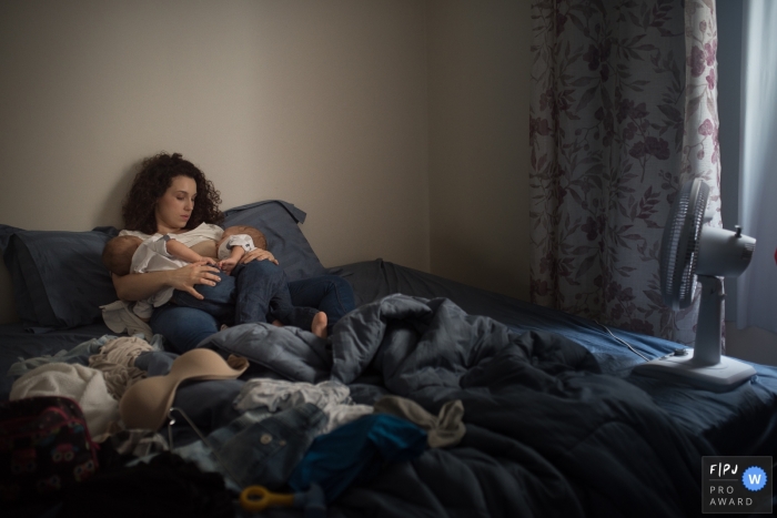 Une mère est assise sur un lit et tient ses deux bébés sur cette photo d'un photojournaliste de la famille Pernambuco.