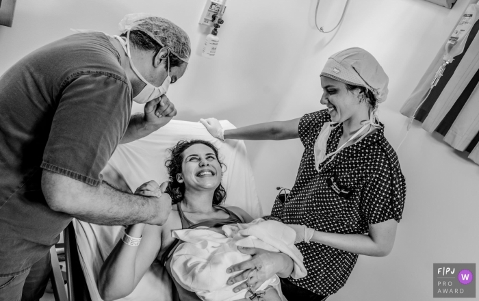 Une mère sourit à son mari alors qu’elle tient son bébé pour la première fois à l’hôpital sur cette image en noir et blanc réalisée par une photographe de naissance à Rio de Janeiro.