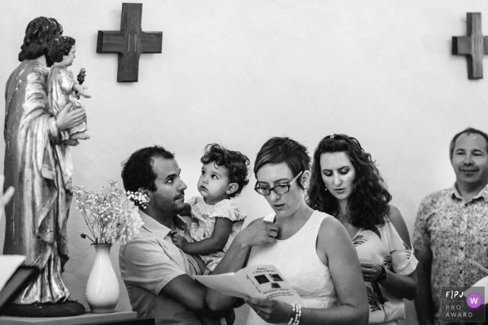 A family reads from a program in church in this black and white photo by a Paris family photographer. 