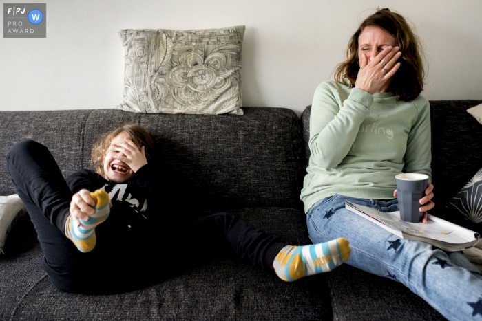 Photo by: <a href="https://www.fpja.com/documentary-family-photography-contests/gonda-meurs/noord-holland/2081451">Gonda Meurs - Netherlands</a> A mother and daughter laugh together on a couch in this FPJA award-winning picture by a Netherlands family photographer.