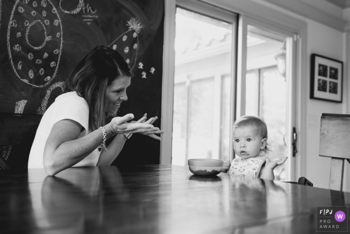 A mother shrugs at her baby girl who sits at the table not eating in this documentary-style family photo captured by a Kansas photographer. 