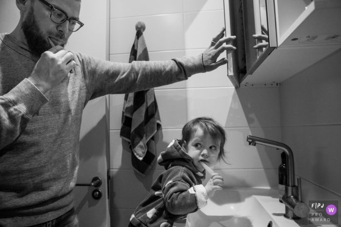 A father and son brush their teeth together in this black and white photo by a Surrey, England family reportage photographer. 