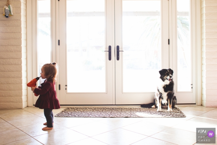 Photo by: <a href="https://www.fpja.com/documentary-family-photography-contests/danielle-daigle/phoenix/2082281">Danielle Daigle - United States</a> A little girl plays with a drill as a dog sits behind her in this award-winning photo by a Phoenix, AZ family photographer.