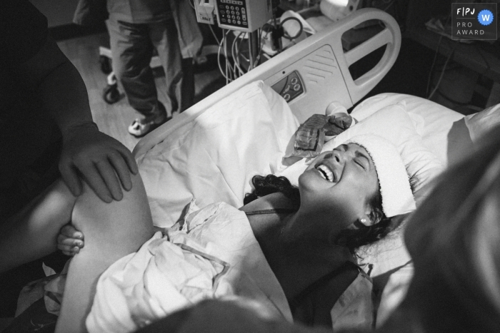 A mother gives birth in a hospital in this black and white awarded image by a Seattle, WA birth photographer. 