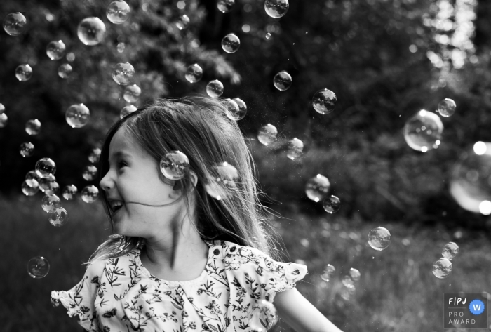 Une petite fille est entourée de bulles dans cette image familiale de style documentaire enregistrée par un photographe bruxellois.