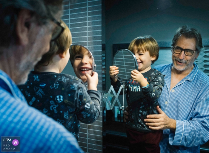 Photo by: <a href="https://www.fpja.com/documentary-family-photography-contests/antonio-calatayud/valencia/2083186">Antonio Calatayud - Spain</a> A little boy is held in front of a mirror as he holds a smaller one up to his face in this Family Photojournalist Association contest awarded photo created by a Valencia, Spain family photographer.