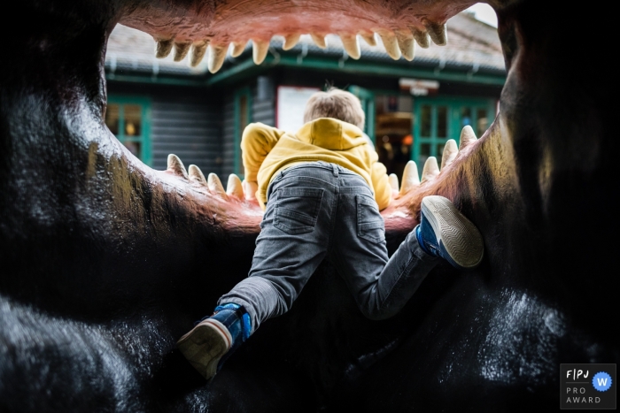 Photo by: <a href="https://www.fpja.com/documentary-family-photography-contests/alice-chapman/cambridgeshire/2083431">Alice Chapman - United Kingdom</a> A boy climbs inside the mouth of a fake dinosaur in this photograph created by a Cambridgeshire, England family photojournalist.