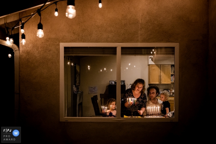 Photo by: <a href="https://www.fpja.com/documentary-family-photography-contests/samantha-ellison/orange-county/2083751">Samantha Ellison - United States</a> A family lights candles on a menorah inside their home in this FPJA award-winning picture by an Orange County, CA family photographer.
