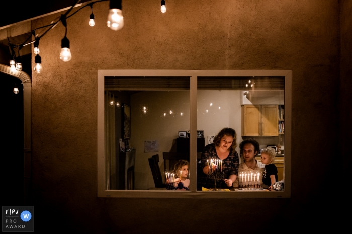 Une famille allume des bougies sur une menorah dans sa maison dans cette photo primée du FPJA par un photographe de famille du comté d'Orange, en Californie.