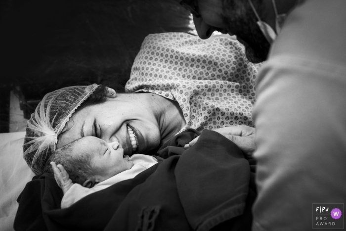 A woman holds her baby for the first time in the hospital in this black and white photo by a Minas Gerais, Brazil reportage-style family birth photographer.