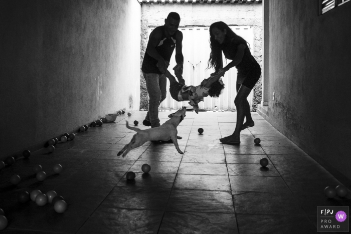 Une mère et un père balancent leur enfant entre eux alors qu'un chien les rejoint sur cette photo prise par un photographe de famille primé du Minas Gerais.