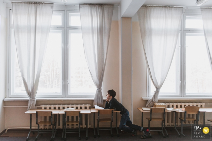 Photo by: <a href="https://www.fpja.com/documentary-family-photography-contests/elena-petrova/saint-petersburg/2084896">Elena Petrova - Russia</a> This photo of a young child staring out the window in a classroom was captured by a Saint-Petersburg family photojournalist