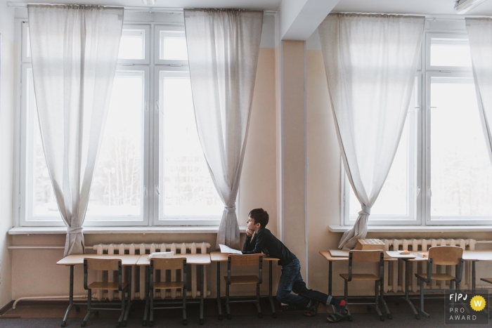 This photo of a young child staring out the window in a classroom was captured by a Saint-Petersburg family photojournalist 