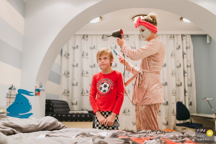 Saint-Petersburg documentary family photographer captured this photo of a mom dressed in pajamas and a face mask styling her child's hair in an ocean themed bedroom