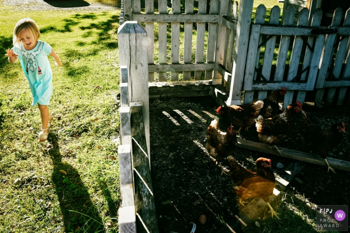 Photo by: <a href="https://www.fpja.com/documentary-family-photography-contests/adeline-leonti/montreal/2085031">Adeline Leonti - Canada</a> A girl plays outside next to a chicken pen in this documentary-style family image recorded by a Montreal, Quebec photographer.