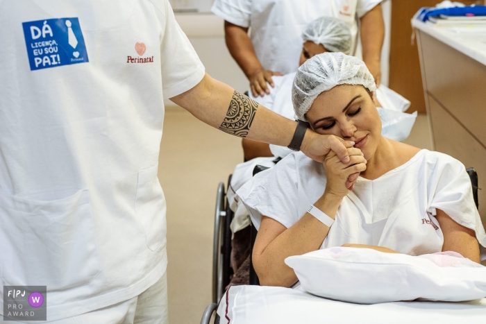 Photo by: <a href="https://www.fpja.com/documentary-family-photography-contests/claudia-ruiz/rio-de-janeiro/2085086">Claudia Ruiz - Brazil</a> A pregnant woman sits in a wheelchair and holds someone's hand in this photo by a Rio de Janeiro, Brazil birth photographer.