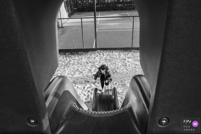 A little girl tries to run back up a slide in this picture captured by a Los Angeles, CA family photojournalist. 