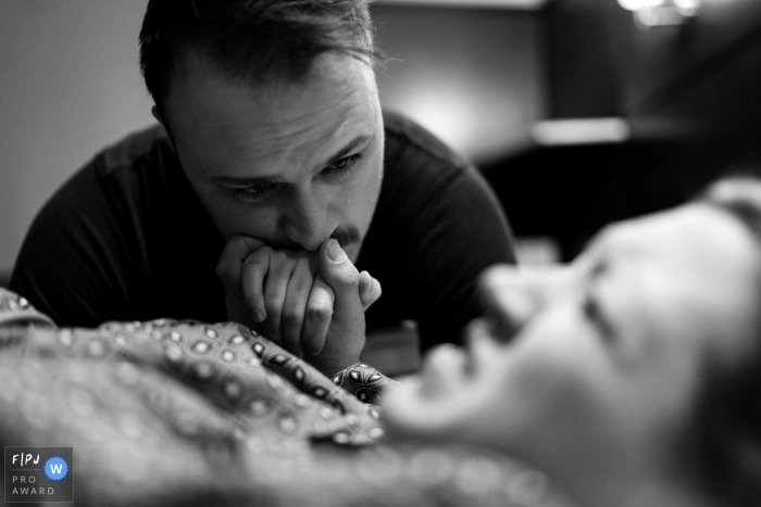 Photo by: <a href="https://www.fpja.com/documentary-family-photography-contests/benjamin-lipford/atlanta/2085611">Benjamin Lipford - United States</a> A husband holds his wife's hand as she gives birth in the hospital in this black and white award-winning photo by an Atlanta, GA photographer.
