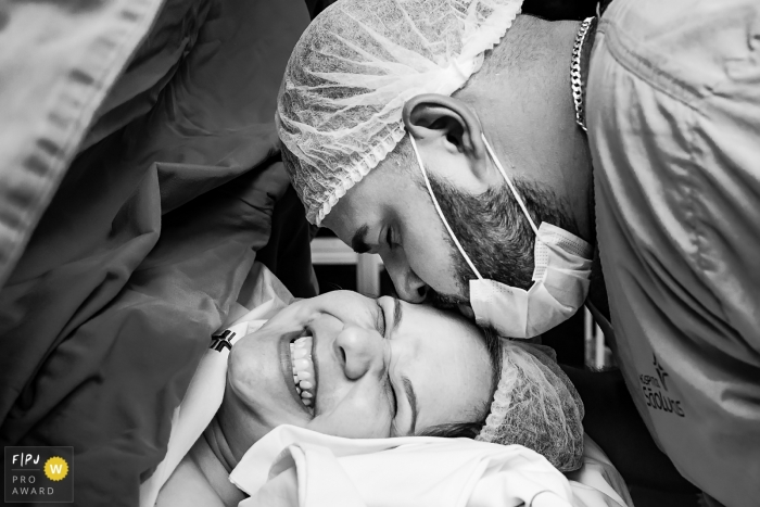 La photojournaliste de l'hôpital Rio Grande do Sul a capturé cette photo en noir et blanc d'un homme embrassant sa partenaire sur le front lors d'une naissance en césarienne