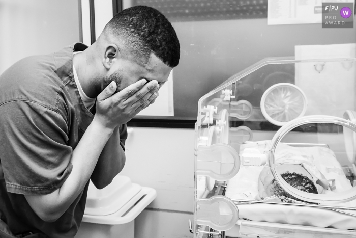 A father gets emotional after seeing his newborn in the hospital for the first time in this black and white image captured by a Rio de Janeiro, Brazil documentary-style birth photographer.