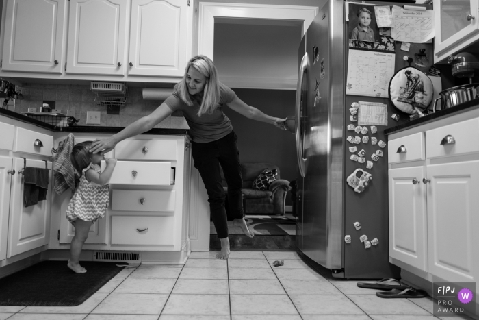 Georgia Family Photography session in home as mom works in the kitchen with a toddler opening drawers.