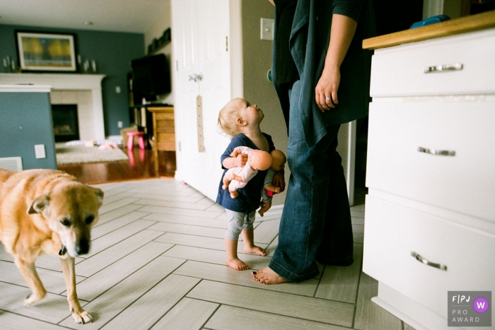 A little girl carries two baby dolls as she looks up at her mother in this Family Photojournalist Association contest awarded photo created by a Boulder, CO family photographer. 