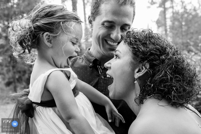 Photo by: <a href="https://www.fpja.com/documentary-family-photography-contests/ron-storer/seattle/2086051">Ron Storer - United States</a> A mother and father smile as they hold their young daughter in this documentary-style family image recorded by a Seattle, WA photographer.
